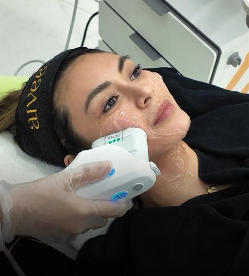 A gloved hand guiding an Ulthera Prime handpiece along a client’s jawline